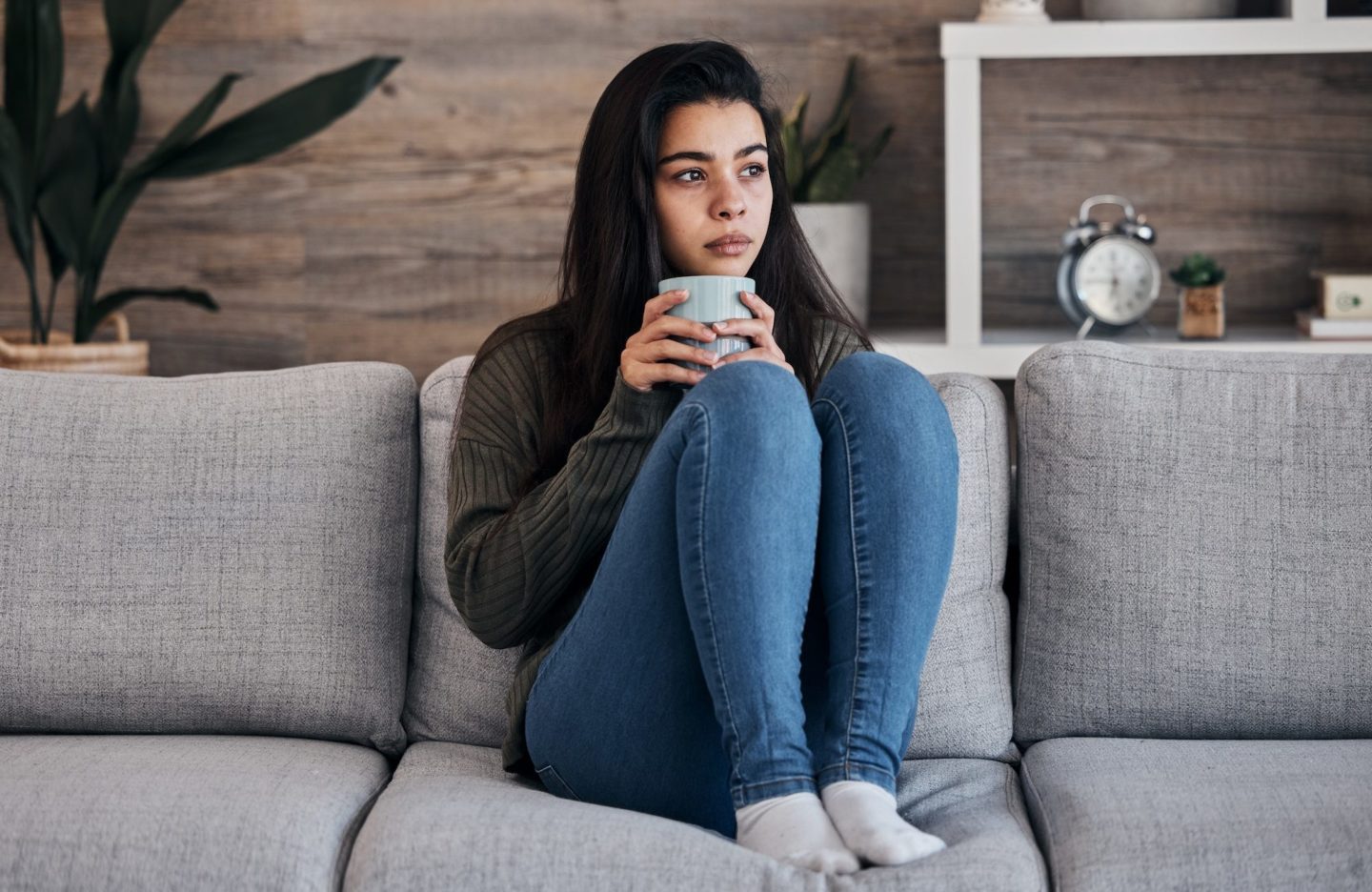 depression-sad-and-woman-with-coffee-on-a-sofa-for-thinking-lonely-and-isolated-in-a-living-room-e1678254761361.jpg